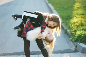 Alleinerziehend: lachende Mutter spielt mit ihrer Tochter im Freien, Symbol für Nähe und Lebensfreude