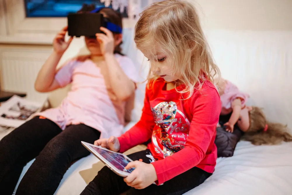 Kinder nutzen Tablet und Virtual-Reality-Brille gleichzeitig – Beispiel für Medienkompetenz bei Kindern und digitale Reizüberflutung