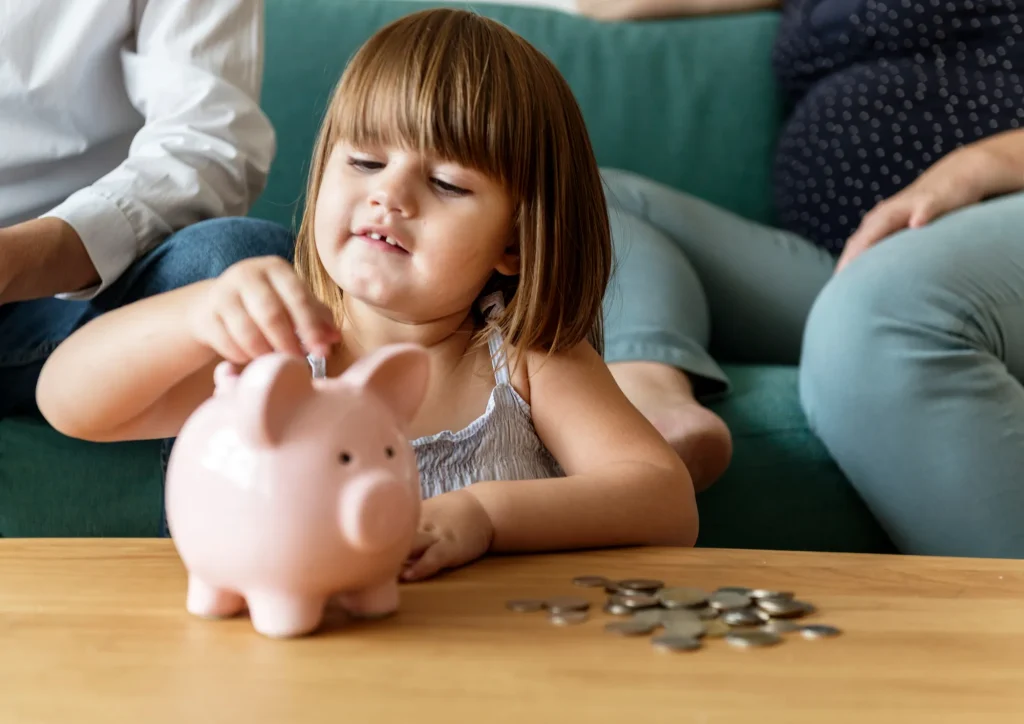 Kind wirft Geld in ein Sparschwein – Symbolbild zur Frühstartrente