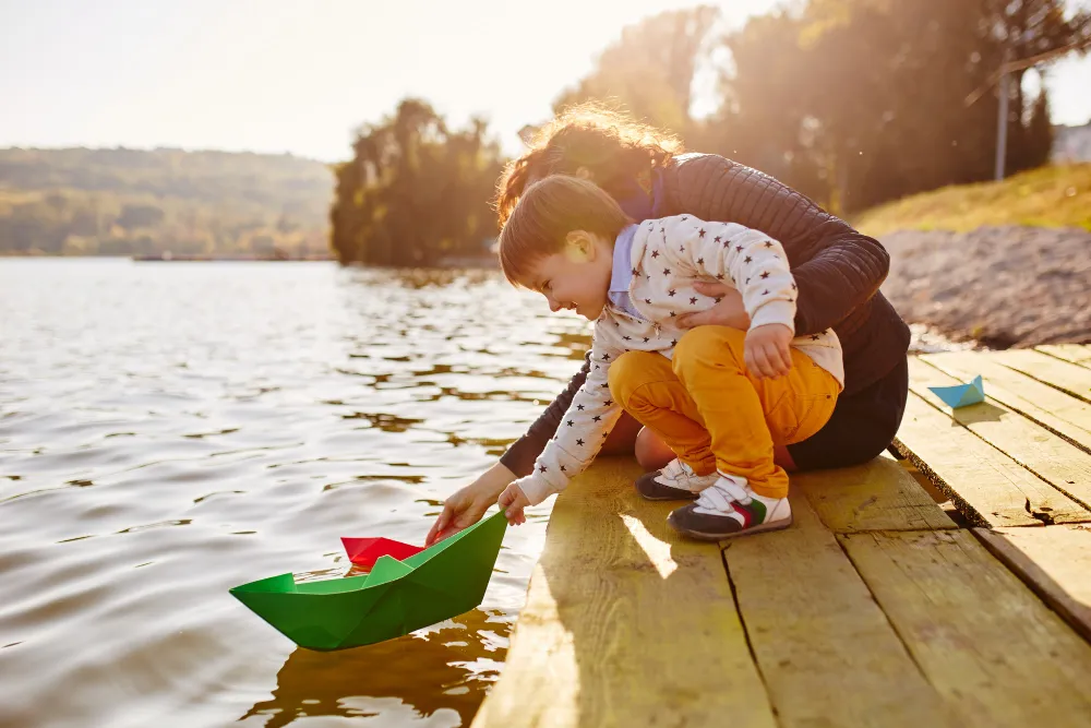 Mutter und Kind lassen ein Papierschiff auf einem See schwimmen – Familienausflug an einem der schönsten Seen Deutschlands.