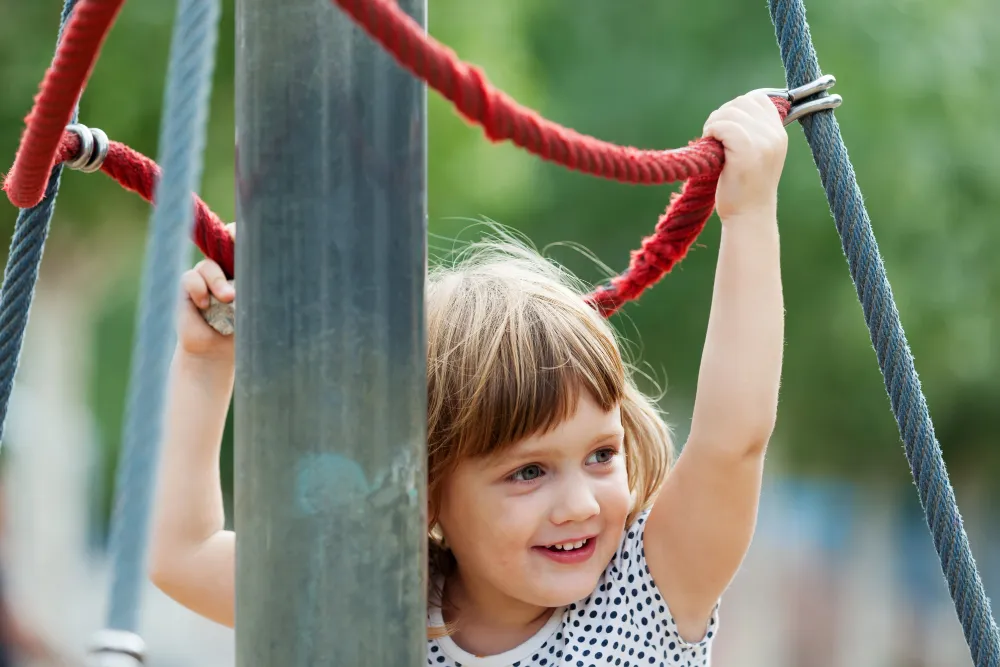 Kind klettert an einem Klettergerüst im Freien