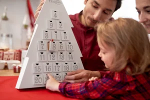 Kind öffnet gemeinsam mit seinen Eltern einen Adventskalender in der Weihnachtszeit.